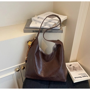 Detailed view of the soft brown leather tote bag with a yellow floral charm accessory