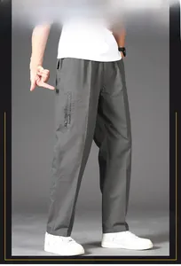 Detail of grey cotton trousers featuring elastic waistband and side zipper pockets