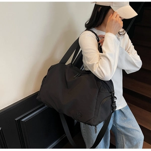Detailed view of a black waterproof nylon travel bag worn crossbody by a model