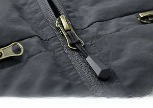 Close-up of durable bronze metal zipper with woven puller on men's cargo vest fabric