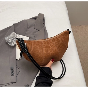 Detail of a brown leopard print crescent bag with leather strap and knot accent