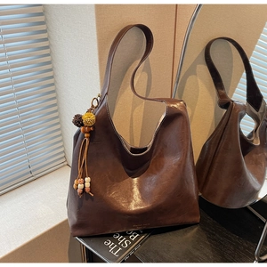 Detail of dark brown PU hobo bag featuring wood bead charms and brand lettering