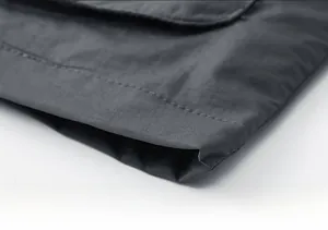 Macro shot of precise stitching on the hem of a dark grey quick-dry tactical vest