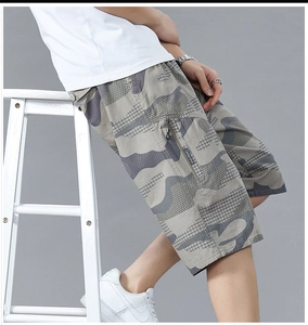 Detail of loose camouflage cargo shorts featuring zipper side pockets and cotton fabric
