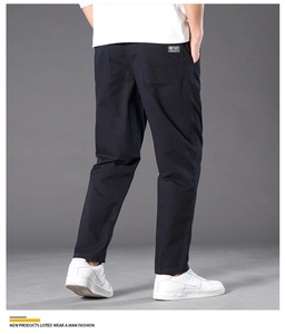 Detail view of navy blue straight-leg cotton trousers with a back pocket woven label
