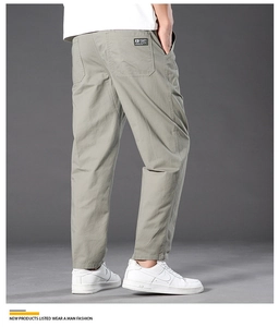 Detail of gray-green men's casual cotton pants showing back pocket label and straight cut