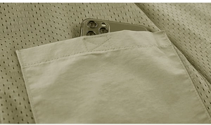 Macro detail of breathable mesh and large functional pocket holding a mobile phone