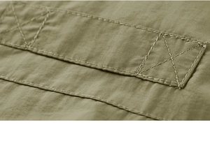 Close-up of durable reinforced cross-stitching on military green tactical fishing vest