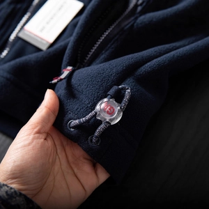 Dark blue fleece jacket hem with adjustable elastic drawstring and branded plastic toggles