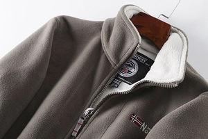 Close-up of grey fleece jacket with warm white faux shearling lining and embroidery