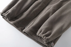 Detail of gray fleece jacket featuring adjustable drawstring toggle and elastic cuffs