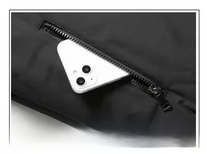 Detail view of large zipper pocket on black winter jacket with smartphone inside