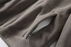 Detail of high-density fleece jacket featuring a smooth resin zipper and secure side pocket