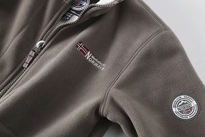 Close-up of gray-brown fleece jacket with high collar and scandinavian embroidery