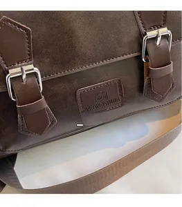 Detailed close-up of dark brown vintage leather texture and silver metal buckles on the bag