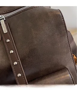 Detail shot of vintage coffee leather backpack with silver zippers and metal rivet accents