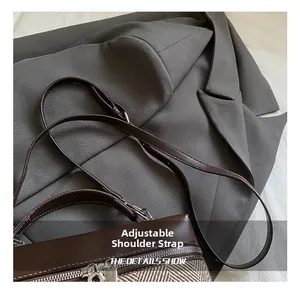 Detail of adjustable shoulder strap and textured fabric on contrast stitching handbag
