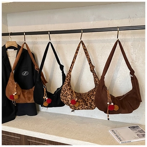 Detail view of four vintage hobo bags in suede and leopard print with fuzzy pom-pom charms
