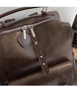 Detail of vintage brown leather backpack showing dual metal zippers with rivet tassels