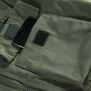 Army green military flight jacket with large utility pocket holding a smartphone