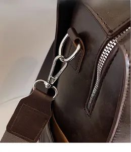 Detail of silver metal hooks and high-quality oil-wax leather texture on a brown backpack