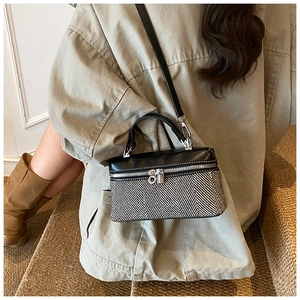 Femme portant un petit sac bandoulière bicolore à motif chevrons en décor automnal