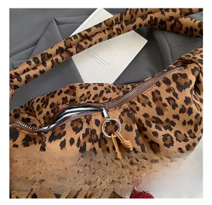 Macro view of leopard print handbag with silver ring zipper and plush red ball charm