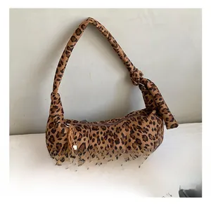 Detail showing leopard print texture and decorative plush ball charm on crescent bag