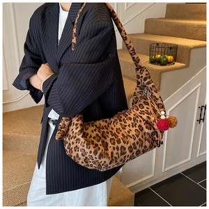 Detail of leopard print shoulder bag with red plush charms and drawstring accent