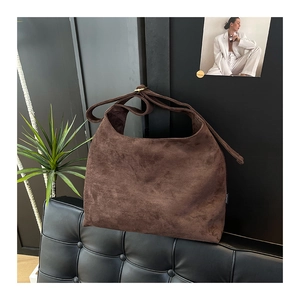 Dettaglio della borsa hobo in pelle scamosciata marrone scuro su un divano in pelle