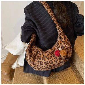Detail of trendy leopard print hobo bag with red pompom charm worn over a black blazer