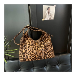 Dettaglio della borsa tote scamosciata leopardata con tracolla larga su parete