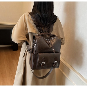 Detail view of the vintage brown leather backpack worn with a classic beige trench coat