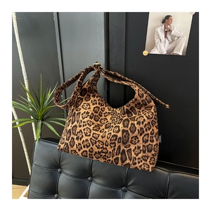 Dettaglio della borsa shopper leopardata con etichetta FASHION su un divano in pelle