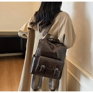 Close-up of a vintage brown PU leather backpack featuring metal buckles and side pockets