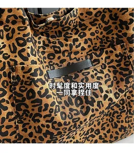 Detailed close-up of leopard print canvas fabric with black leather decorative strap
