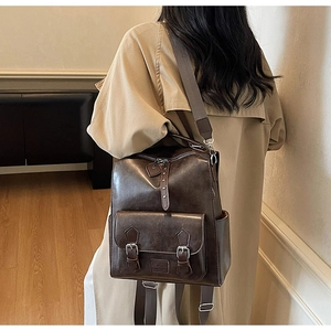 Detail view of vintage dark brown faux leather backpack with metallic buckle front pocket