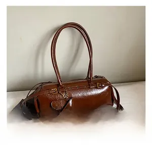 Detail view of a dark brown glossy cylinder baguette bag with metallic eyelet straps