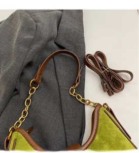 Detail of green suede underarm bag with brown trim, gold chain and adjustable long strap