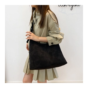 Dettaglio di una grande borsa tote in pelle scamosciata nera con etichetta Fashion su modella