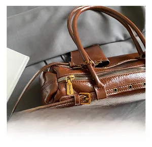 Detail of vintage brown leather handbag featuring glossy texture and premium gold zippers