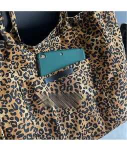 Detail of leopard print tote bag showing large exterior pocket holding a green tablet