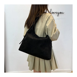 Dettaglio di una grande borsa tote nera in pelle scamosciata indossata dalla modella