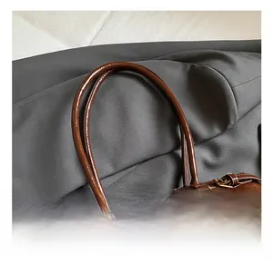 Detail of dark brown leather handbag with fine stitching and gold buckle hardware