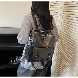 Detail shot of vintage dark grey faux leather backpack with silver rivets and flap pocket