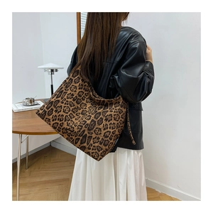 Dettaglio della grande borsa leopardata con giacca di pelle e abito bianco