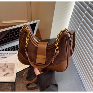 Close-up of retro brown suede crescent bag with gold chain and square metal lock