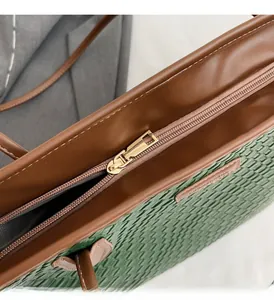 Close-up of woven texture tote with gold zipper and contrasting leather trim details