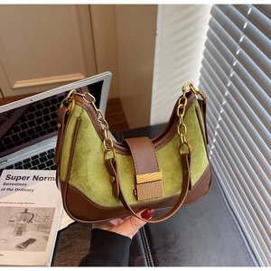 Close-up of green suede and brown leather patchwork shoulder bag with gold chain