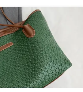 Detail of green woven tote bag featuring brown leather trim and intricate texture